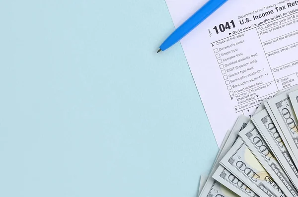 1041 belastingformulier ligt dicht bij honderd dollar biljetten en blauwe pen op een l — Stockfoto