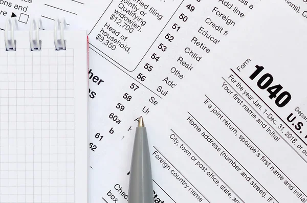 钢笔和笔记本位于1040美国个性化的税表上。 — 图库照片