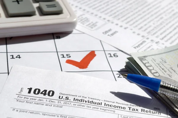 1040 Individual Income Tax Return blank with dollar bills, calculator and pen on calendar page with marked 15th April — Stock Photo, Image