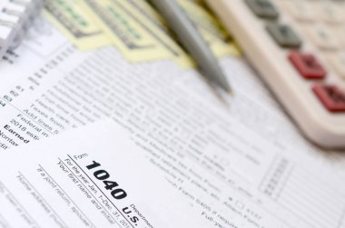 Kalem, defter, hesap makinesi ve dolar faturaları yalanlar üzerine vergi 1040 ABD bireysel gelir vergisi beyannamesi formu var. Vergi ödemek için zaman