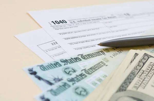 1040 Individual Income tax return form with Refund Check and hundred dollar bills on beige background