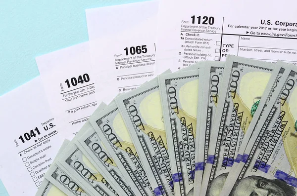 Φορολογικά έντυπα βρίσκονται κοντά σε χαρτονομίσματα των εκατό δολαρίων και μπλε στυλό σε ένα φως — Φωτογραφία Αρχείου