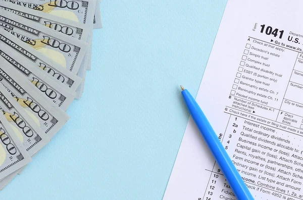 1041 tax form lies near hundred dollar bills and blue pen on a l — 스톡 사진