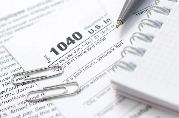 Ручка, ноутбук и долларовые купюры лежат на налоговой форме 1040 — стоковое фото