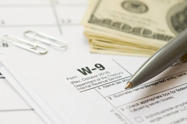 IRS Form W-9 Request for taxpayer identification number and certification blank lies with pen and many hundred dollar bills on calendar page — Stock Photo, Image