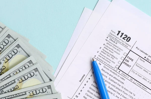 1120 tax form lies near hundred dollar bills and blue pen on a l — 스톡 사진