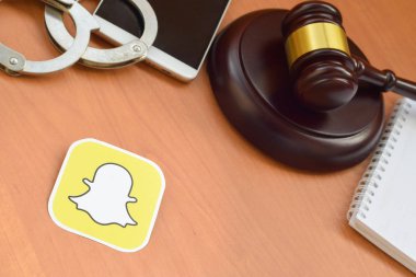 Kharkov, Ukrayna - 17 Şubat 2020: Tahta yargıç tokmağı, akıllı telefon ve kelepçeli Snapchat kağıt logosu. Eğlence davaları konsepti
