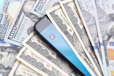 Kharkov, Ukrayna - 6 Şubat 2020: Tiktok uygulamalı akıllı telefon ekranı ve bir sürü yüz dolarlık banknot. İş ve sosyal ağ kavramı