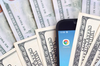 Kharkov, Ukrayna - 6 Şubat 2020: Google Chrome uygulamalı akıllı telefon ekranı ve bir sürü yüz dolarlık banknot. İş ve sosyal ağ kavramı