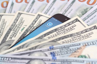 Kharkov, Ukrayna - 6 Şubat 2020: Telgraf uygulamalı akıllı telefon ekranı ve bir sürü yüz dolarlık banknot. İş ve sosyal ağ kavramı