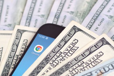 Kharkov, Ukrayna - 6 Şubat 2020: Google Chrome uygulamalı akıllı telefon ekranı ve bir sürü yüz dolarlık banknot. İş ve sosyal ağ kavramı