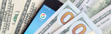Kharkov, Ukrayna - 6 Şubat 2020: Google uygulamalı akıllı telefon ekranı ve bir sürü yüz dolarlık banknot. İş ve sosyal ağ kavramı