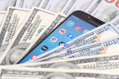Kharkov, Ukrayna - 6 Şubat 2020: Popüler uygulamaları ve bir sürü yüz dolarlık banknotları olan akıllı telefon ekranı. İş ve sosyal ağ kavramı