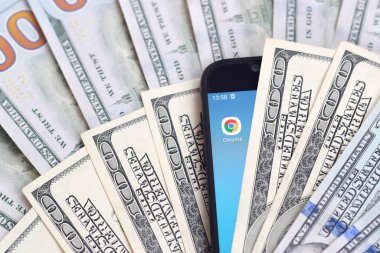 Kharkov, Ukrayna - 6 Şubat 2020: Google Chrome uygulamalı akıllı telefon ekranı ve bir sürü yüz dolarlık banknot. İş ve sosyal ağ kavramı