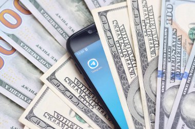 Kharkov, Ukrayna - 6 Şubat 2020: Telgraf uygulamalı akıllı telefon ekranı ve bir sürü yüz dolarlık banknot. İş ve sosyal ağ kavramı