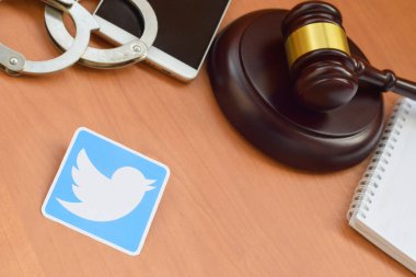 Kharkov, Ukrayna - 17 Şubat 2020: Twitter kağıt logosu ahşap yargıç tokmağı, akıllı telefon ve kelepçe içeriyor. Eğlence davaları konsepti