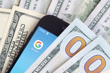 Kharkov, Ukrayna - 6 Şubat 2020: Google uygulamalı akıllı telefon ekranı ve bir sürü yüz dolarlık banknot. İş ve sosyal ağ kavramı