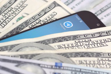 Kharkov, Ukrayna - 6 Şubat 2020: Telgraf uygulamalı akıllı telefon ekranı ve bir sürü yüz dolarlık banknot. İş ve sosyal ağ kavramı