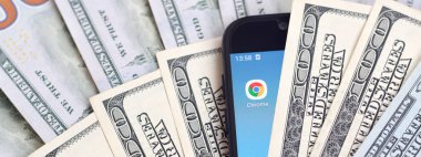 Kharkov, Ukrayna - 6 Şubat 2020: Google Chrome uygulamalı akıllı telefon ekranı ve bir sürü yüz dolarlık banknot. İş ve sosyal ağ kavramı