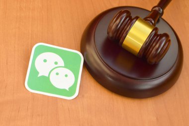 KHARKOV, UKRAINE - FEBRUARY 17, 2020: Wechat paper logo lies with wooden judge gavel. Entertainment lawsuit concept