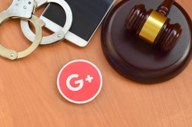 Kharkov, Ukrayna - 17 Şubat 2020: Google + kağıt logosu ahşap yargıç tokmağı, akıllı telefon ve kelepçeli. Eğlence davaları konsepti