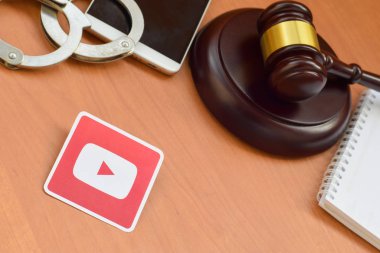 Kharkov, Ukrayna - 17 Şubat 2020: Tahta yargıç tokmağı, akıllı telefon ve kelepçeli Youtube kağıt logosu. Eğlence davaları konsepti