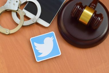 Kharkov, Ukrayna - 17 Şubat 2020: Twitter kağıt logosu ahşap yargıç tokmağı, akıllı telefon ve kelepçe içeriyor. Eğlence davaları konsepti