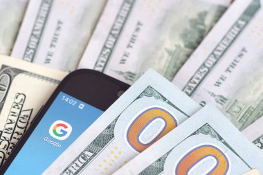 Kharkov, Ukrayna - 6 Şubat 2020: Google uygulamalı akıllı telefon ekranı ve bir sürü yüz dolarlık banknot. İş ve sosyal ağ kavramı