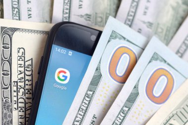 Kharkov, Ukrayna - 6 Şubat 2020: Google uygulamalı akıllı telefon ekranı ve bir sürü yüz dolarlık banknot. İş ve sosyal ağ kavramı