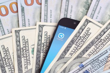 Kharkov, Ukrayna - 6 Şubat 2020: Telgraf uygulamalı akıllı telefon ekranı ve bir sürü yüz dolarlık banknot. İş ve sosyal ağ kavramı