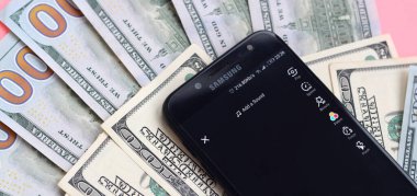 Kharkov, Ukrayna - 16 Şubat 2020: Tiktok uygulamalı akıllı telefon ekranı ve bir sürü yüz dolarlık banknot. İş ve sosyal ağ kavramı