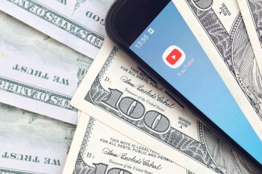 Kharkov, Ukrayna - 6 Şubat 2020: Youtube uygulamalı akıllı telefon ekranı ve bir sürü yüz dolarlık banknotlar. İş ve sosyal ağ kavramı