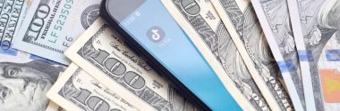 Kharkov, Ukrayna - 6 Şubat 2020: Tiktok uygulamalı akıllı telefon ekranı ve bir sürü yüz dolarlık banknot. İş ve sosyal ağ kavramı