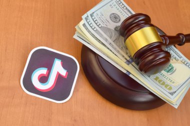 Kharkov, Ukrayna - 17 Şubat 2020: Tiktok kağıt logosu yargıç tokmağı ve yüz dolarlık banknotlarla yatar. Eğlence davaları konsepti