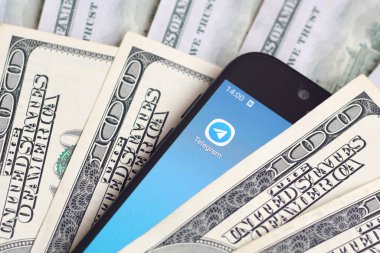 Kharkov, Ukrayna - 6 Şubat 2020: Telgraf uygulamalı akıllı telefon ekranı ve bir sürü yüz dolarlık banknot. İş ve sosyal ağ kavramı