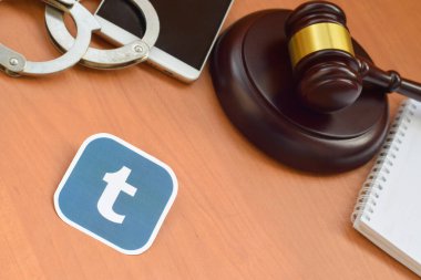 Kharkov, Ukrayna - 17 Şubat 2020: Tumblr kağıt logosu ahşap yargıç tokmağı, akıllı telefon ve kelepçeli. Eğlence davaları konsepti
