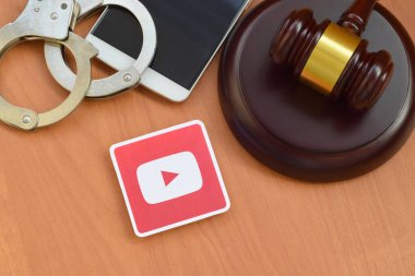 Kharkov, Ukrayna - 17 Şubat 2020: Tahta yargıç tokmağı, akıllı telefon ve kelepçeli Youtube kağıt logosu. Eğlence davaları konsepti