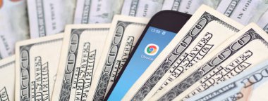 Kharkov, Ukrayna - 6 Şubat 2020: Google Chrome uygulamalı akıllı telefon ekranı ve bir sürü yüz dolarlık banknot. İş ve sosyal ağ kavramı