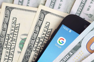 Kharkov, Ukrayna - 6 Şubat 2020: Google uygulamalı akıllı telefon ekranı ve bir sürü yüz dolarlık banknot. İş ve sosyal ağ kavramı