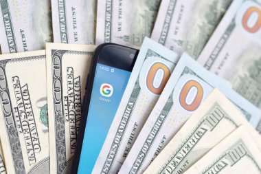 Kharkov, Ukrayna - 6 Şubat 2020: Google uygulamalı akıllı telefon ekranı ve bir sürü yüz dolarlık banknot. İş ve sosyal ağ kavramı