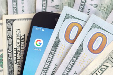 Kharkov, Ukrayna - 6 Şubat 2020: Google uygulamalı akıllı telefon ekranı ve bir sürü yüz dolarlık banknot. İş ve sosyal ağ kavramı