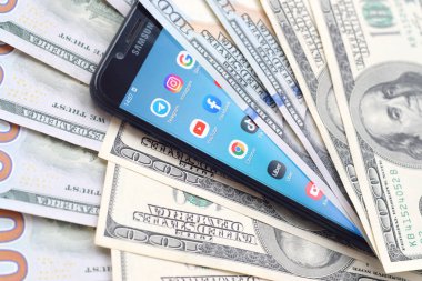 Kharkov, Ukrayna - 6 Şubat 2020: Popüler uygulamaları ve bir sürü yüz dolarlık banknotları olan akıllı telefon ekranı. İş ve sosyal ağ kavramı