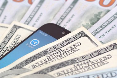 Kharkov, Ukrayna - 6 Şubat 2020: Telgraf uygulamalı akıllı telefon ekranı ve bir sürü yüz dolarlık banknot. İş ve sosyal ağ kavramı