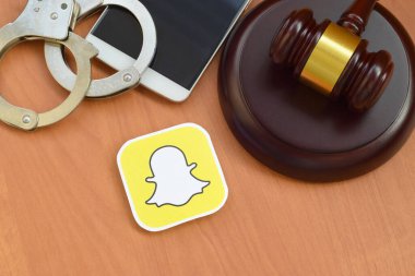 Kharkov, Ukrayna - 17 Şubat 2020: Tahta yargıç tokmağı, akıllı telefon ve kelepçeli Snapchat kağıt logosu. Eğlence davaları konsepti