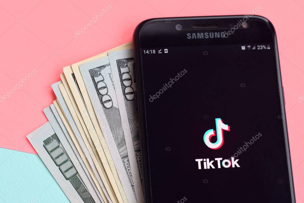 KHARKOV, UKRAINE - FEBRUARY 16, 2020: Tiktok application on samsung smartphone screen and dollar bills. TikTok is a popular video-sharing social networking service owned by ByteDance