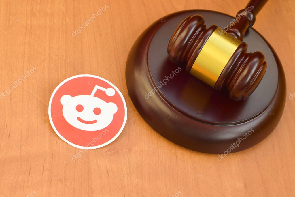 KHARKOV, UKRAINE - FEBRUARY 17, 2020: Reddit paper logo lies with wooden judge gavel. Entertainment lawsuit concept