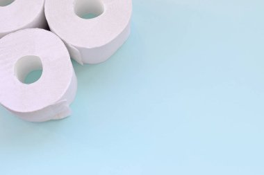 Coronavirus pandemik panik alışveriş konsepti. Açık mavi arka planda birkaç yeni tuvalet kağıdı rulosu. Metin için kopyalama alanı olan minimalist düz konum