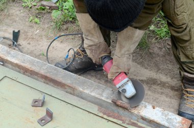 Dışarıdaki çelik yapıda elektrikli tekerlek gıcırdıyor. Koruyucu eldivenli eski bir işçi metal kapıyı öğütücüyle kesiyor. Demir öğütürken kıvılcımlar