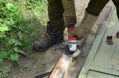 Dışarıdaki çelik yapıda elektrikli tekerlek gıcırdıyor. Koruyucu eldivenli eski bir işçi metal kapıyı öğütücüyle kesiyor. Demir öğütürken kıvılcımlar