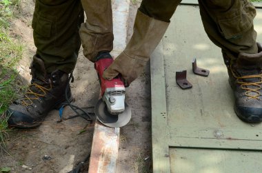 Dışarıdaki çelik yapıda elektrikli tekerlek gıcırdıyor. Koruyucu eldivenli eski bir işçi metal kapıyı öğütücüyle kesiyor. Demir öğütürken kıvılcımlar